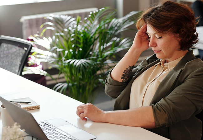 Schmerzen im Daumen: Frau am Laptop mit Kopfschmerzen. Bild: Pexels/Marcus Aurelius
